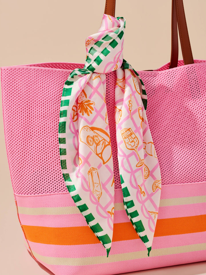 Pink tote bag with a decorative scarf tied around it on a beige background