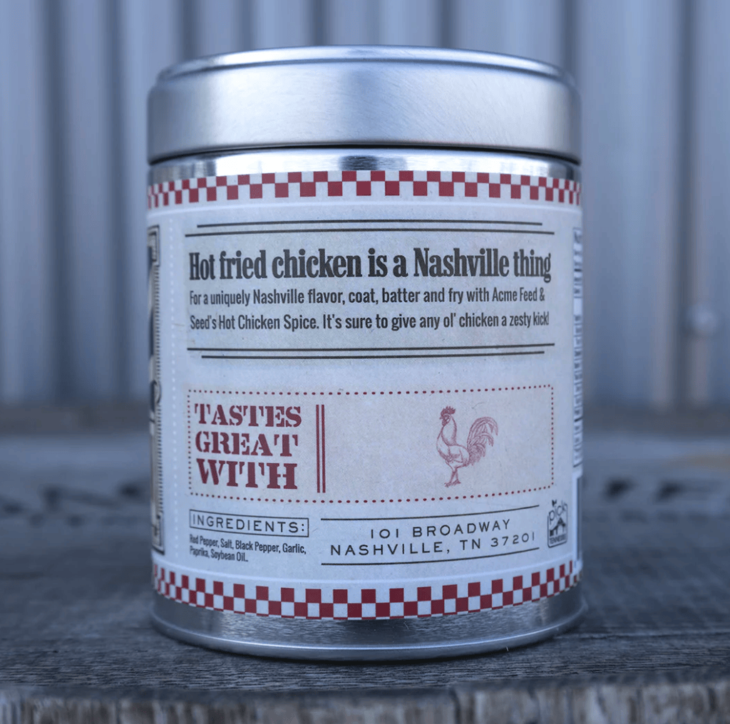A cylindrical metal spice tin with a silver lid and a white label featuring red and black text, placed on a weathered wooden surface against a corrugated metal backdrop.