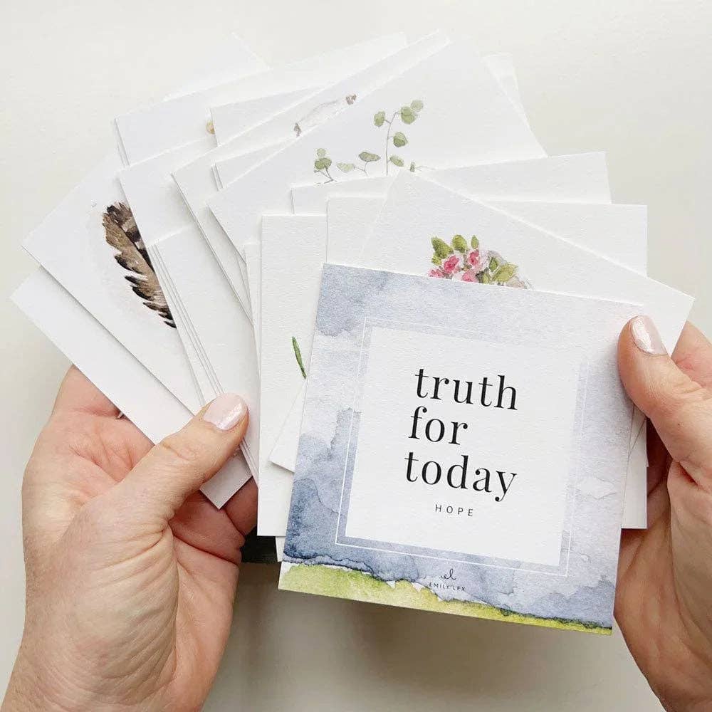 Hands holding a stack of cards with inspirational messages on a light background