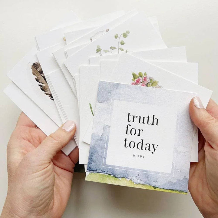 Hands holding a stack of cards with inspirational messages on a light background