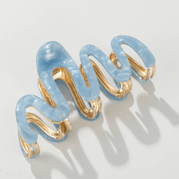Light blue claw hair clip with gold accents on a white background