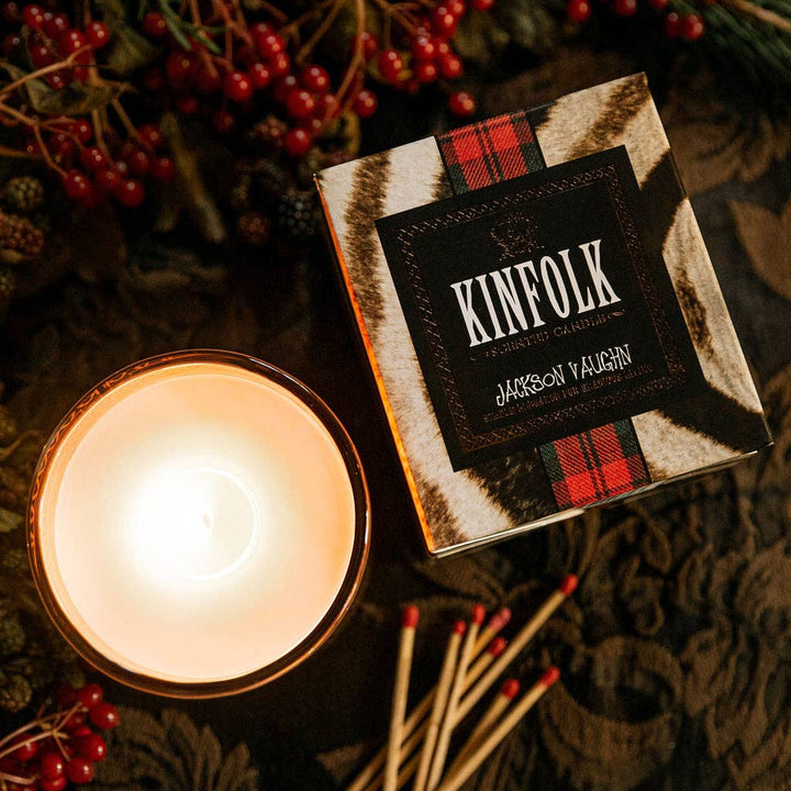 Kinfolk candle with matches and berries on a textured surface