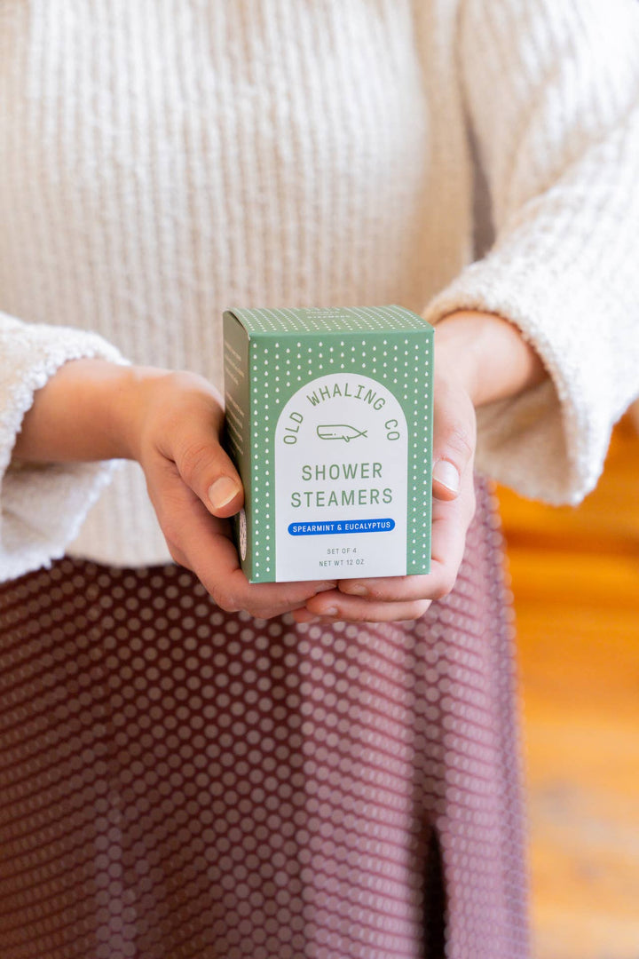 Person holding a box of 'Old Whaling Co. Shower Steamers' with a neutral background