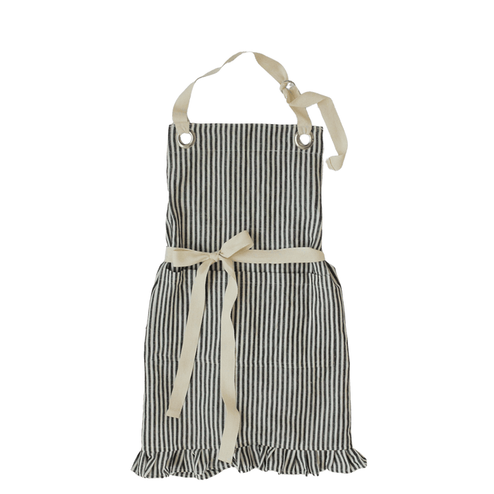 A children's bib-style apron with vertical black and off-white stripes, featuring an off-white neck strap, waist tie with bow, and ruffled hem, shown against a solid dark green background.