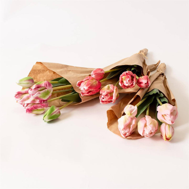 Bouquet of pink tulips wrapped in brown paper on a white background