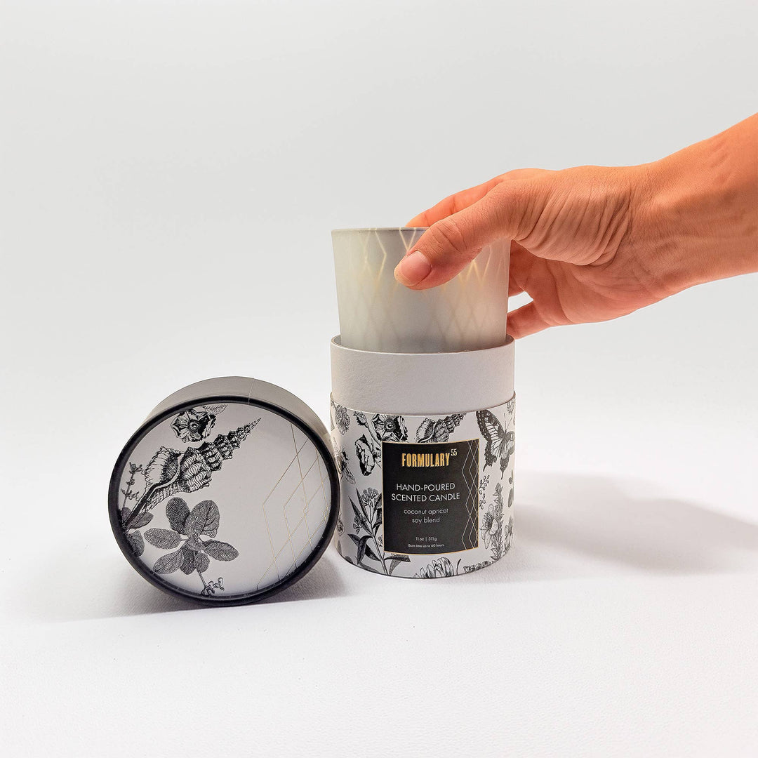 Hand holding a candle with a decorative label on a white background