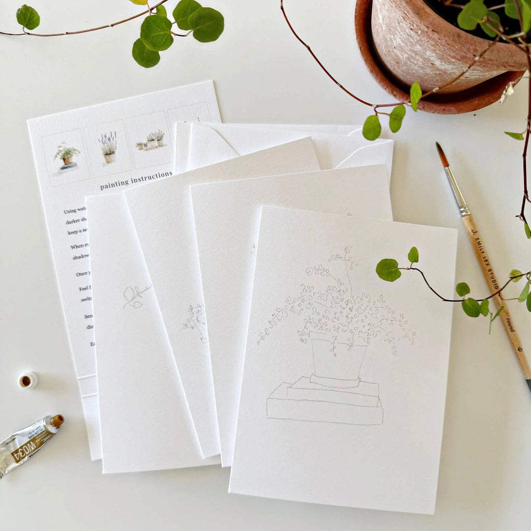 Set of white cards with plant illustrations and paintbrush on a light surface