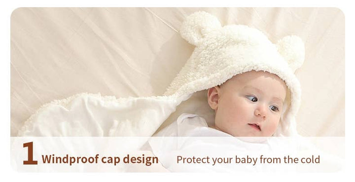 A baby wearing a white plush hooded cap with bear ears, lying on a soft cream blanket. Text at the bottom reads '1 Windproof cap design' and 'Protect your baby from the cold'.