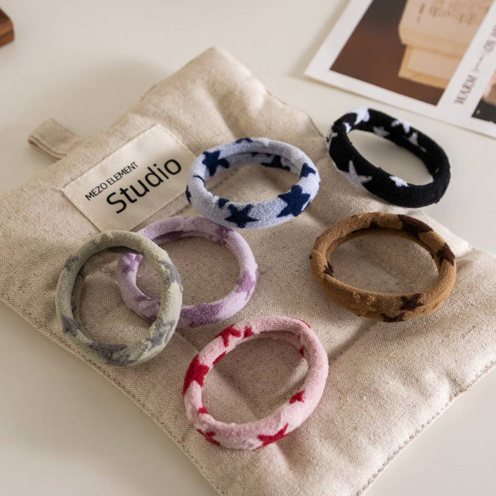 Set of colorful hair ties on a beige fabric with 'Studio' branding.
