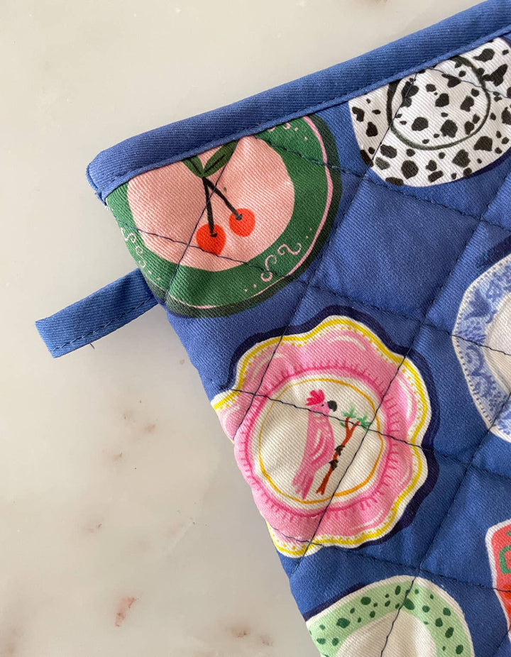 Quilted pot holder with colorful designs on a light wooden surface