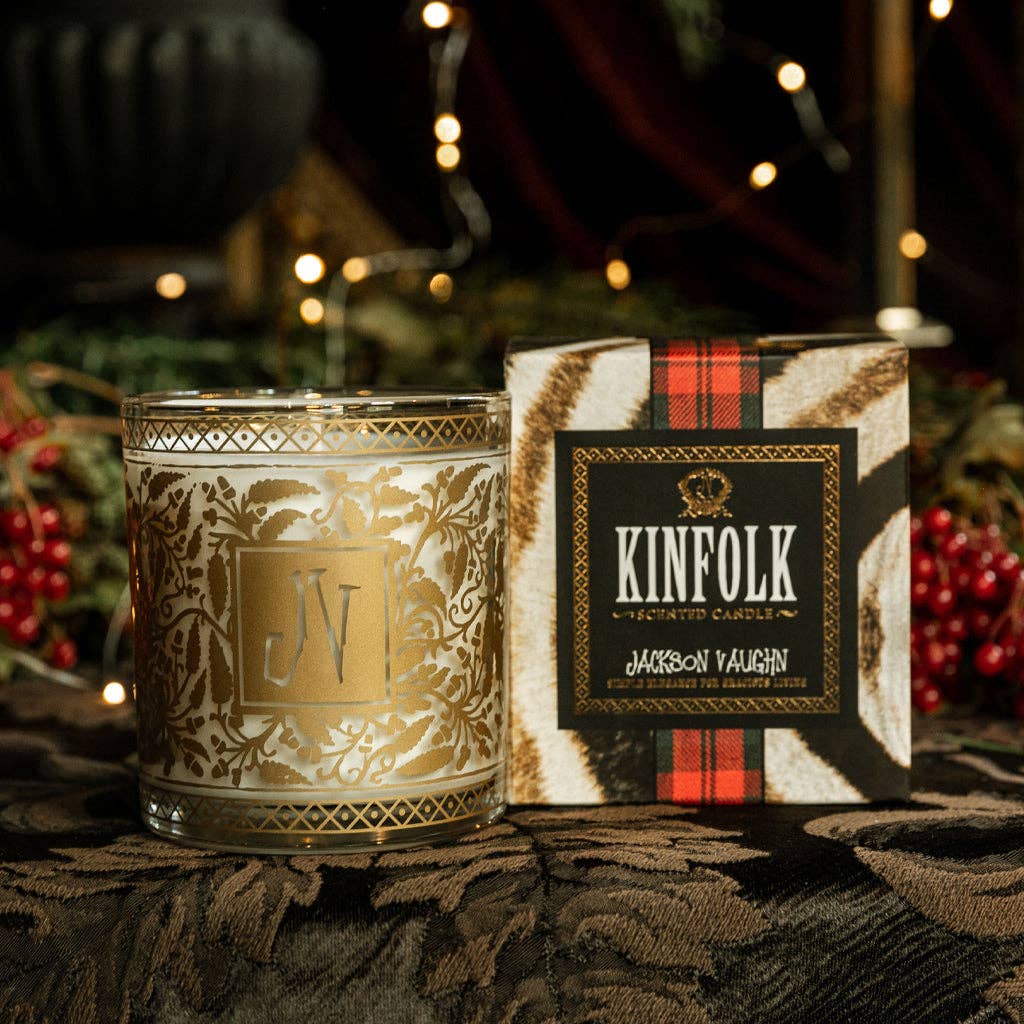 Decorative candle with intricate design next to its packaging box featuring 'KINFOLK' branding.