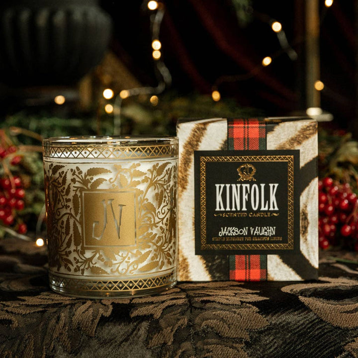 Decorative candle with intricate design next to its packaging box featuring 'KINFOLK' branding.