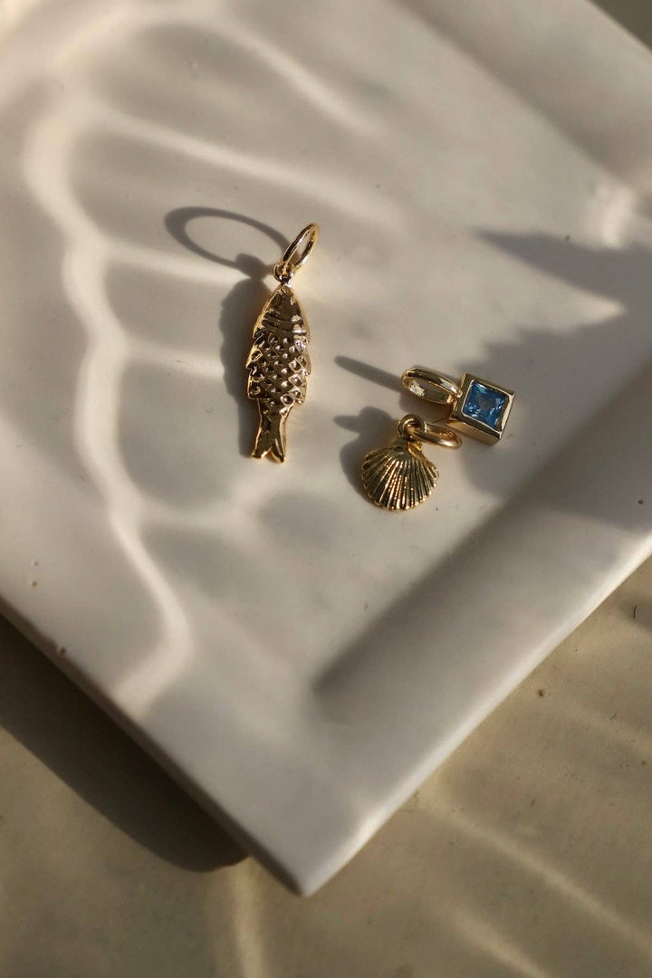 Two gold charms on a white ceramic plate