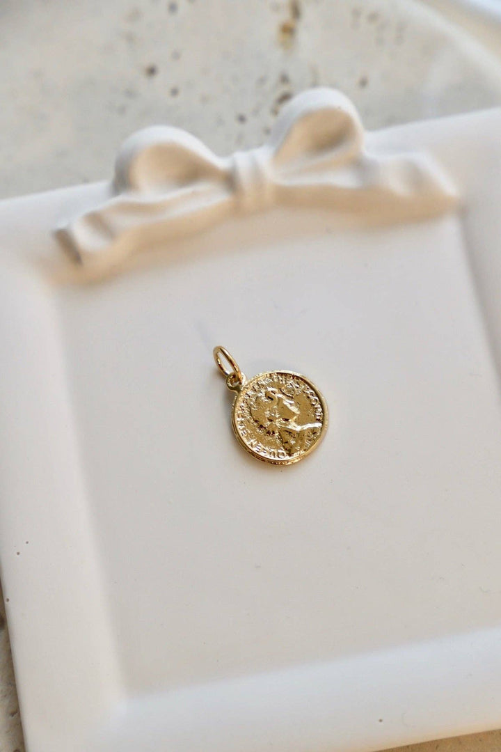 Gold pendant on a white ceramic dish with a bow