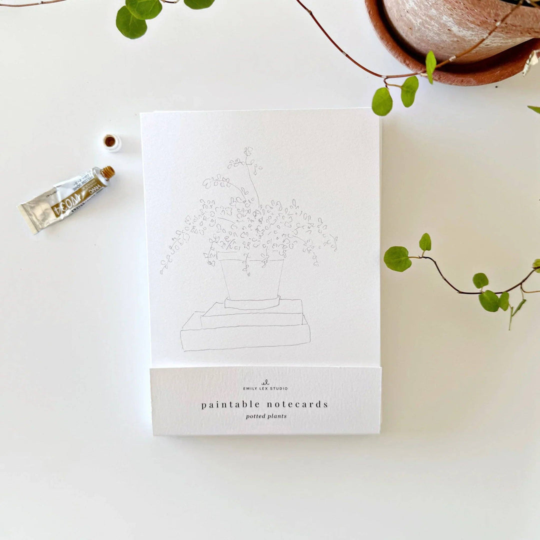Pack of paintable notecards with a plant design on a white surface with greenery.