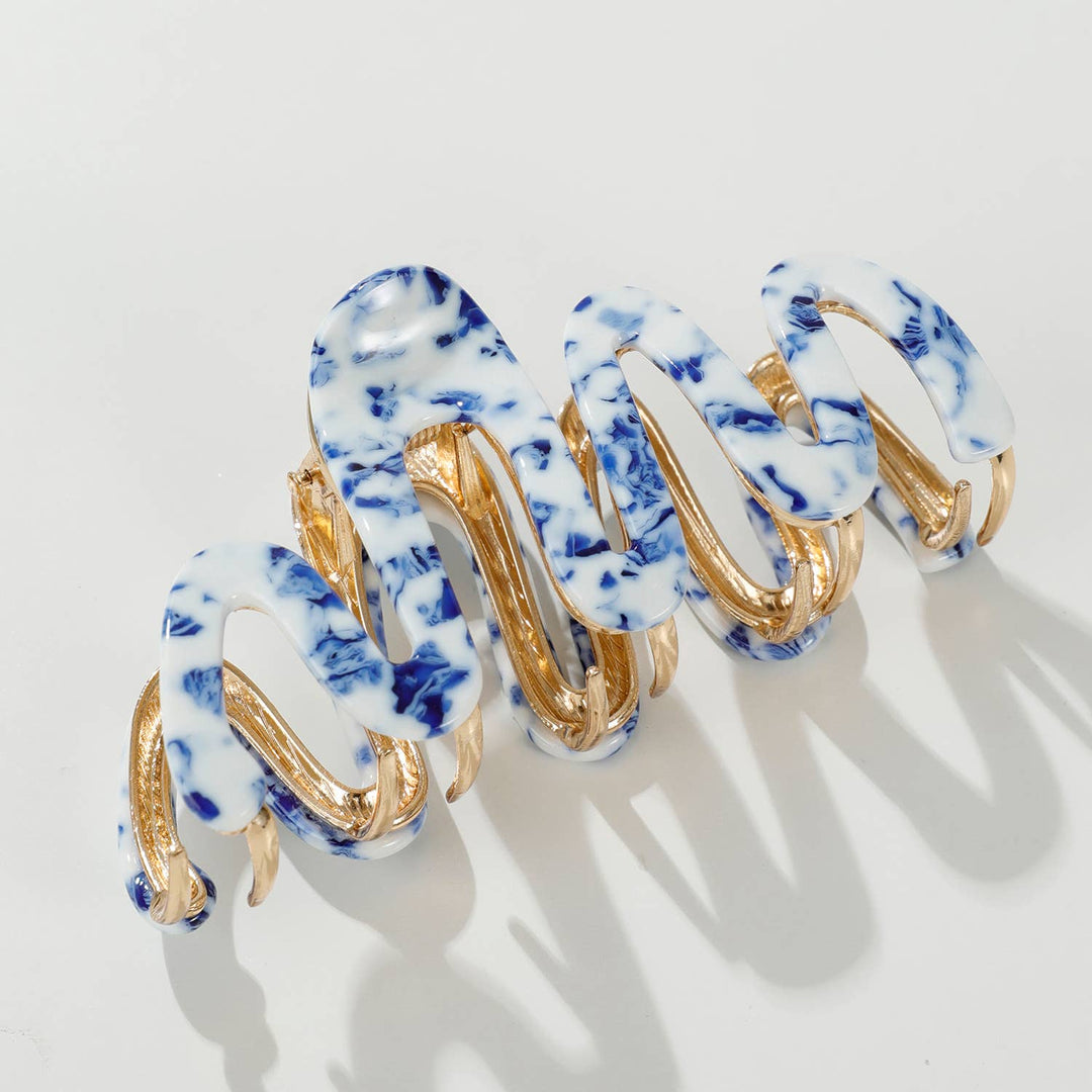 Claw hair clip with blue and white marbled design on a light gray background