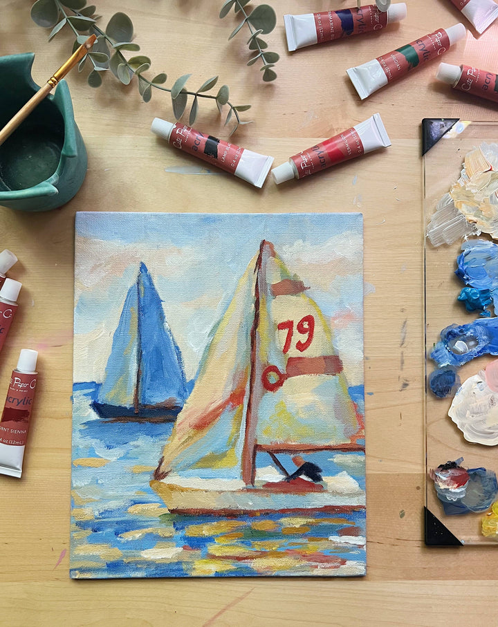 Painting of sailboats on a wooden surface with art supplies