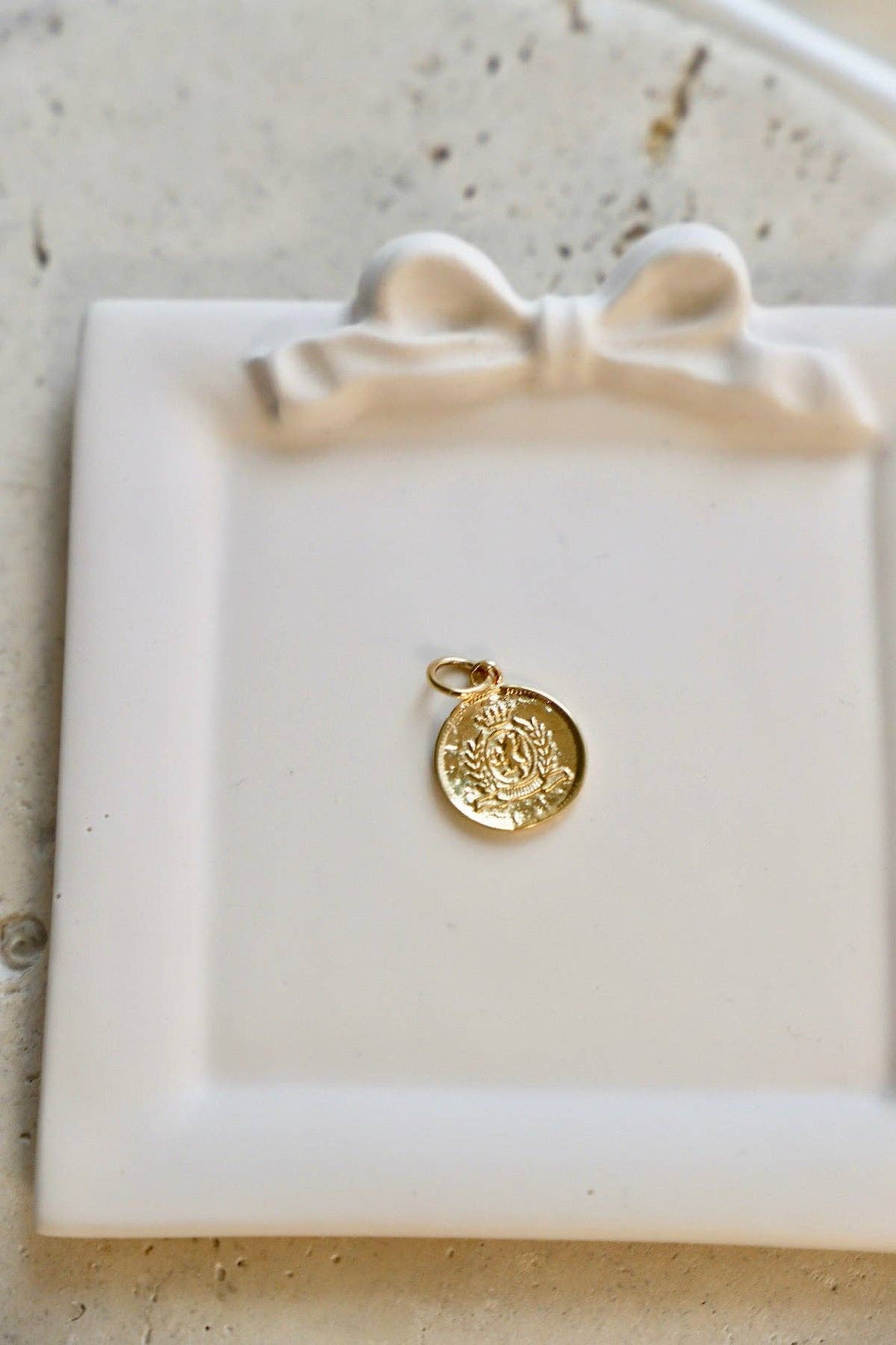 Gold pendant on a white dish with a textured surface