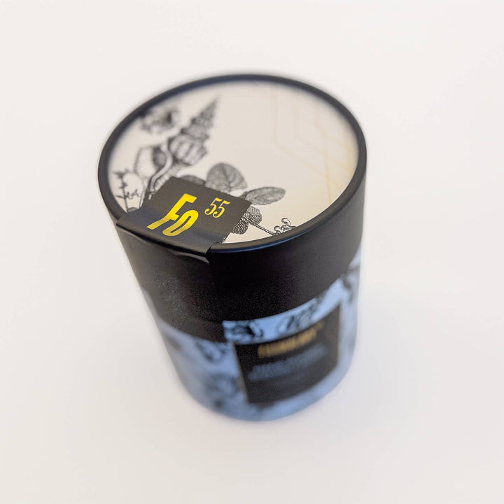 Candle in a decorative container with a visible brand label on a white background