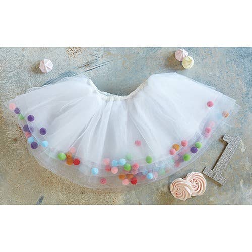 White tutu skirt with colorful pom-poms on a textured surface