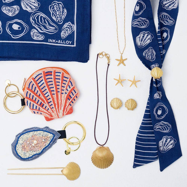 Collection of shell-themed accessories including a scarf, keychain, and necklace on a white background.
