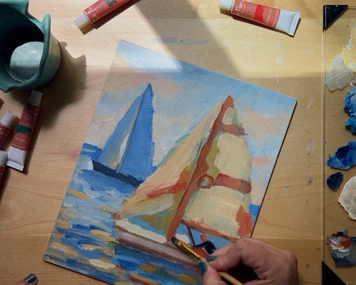 Painting of sailboats on a wooden surface with art supplies.