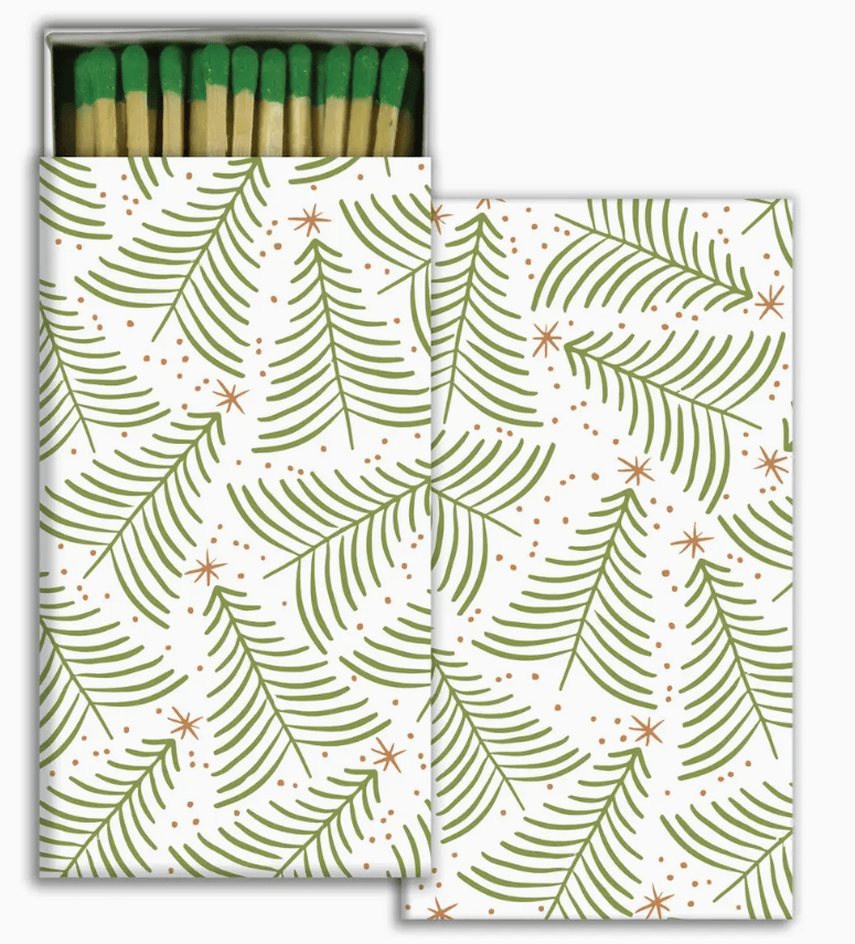 A matchbox-style package and a separate card or insert featuring a white background with an allover pattern of foil christmas trees with gold stars. The top of the package shows green-tipped matches.
