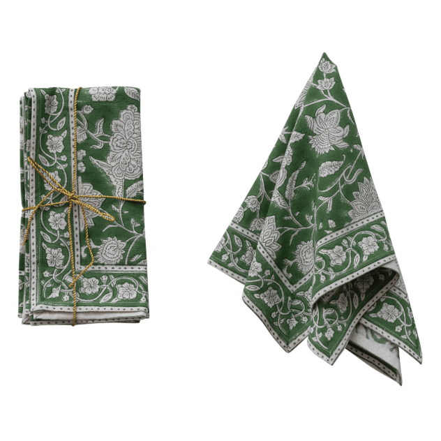 A folded green and white floral patterned cloth, shown both folded and unfolded on a plain white background. The folded version is tied with a thin gold string.