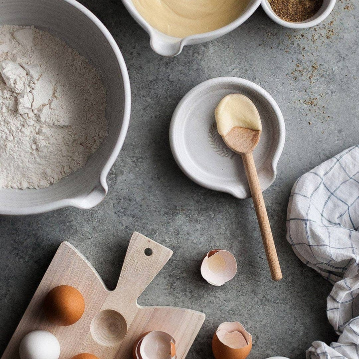 Laurel Spoon Rest with wooden spoon and baking ingredients and eggs with blue and white kitchen towel