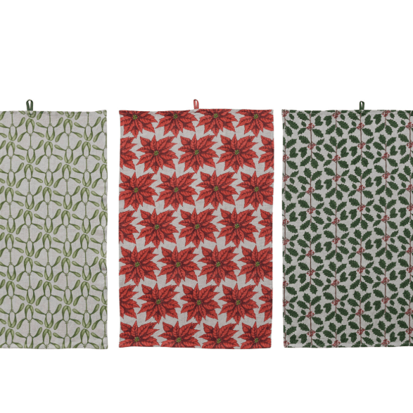 Three hanging fabric tea towels with holiday patterns on a white background: a left towel with green vine motifs on a light beige base, a center towel with red poinsettia motifs on a red and white base, and a right towel with green holly and leaf motifs on a light beige base.