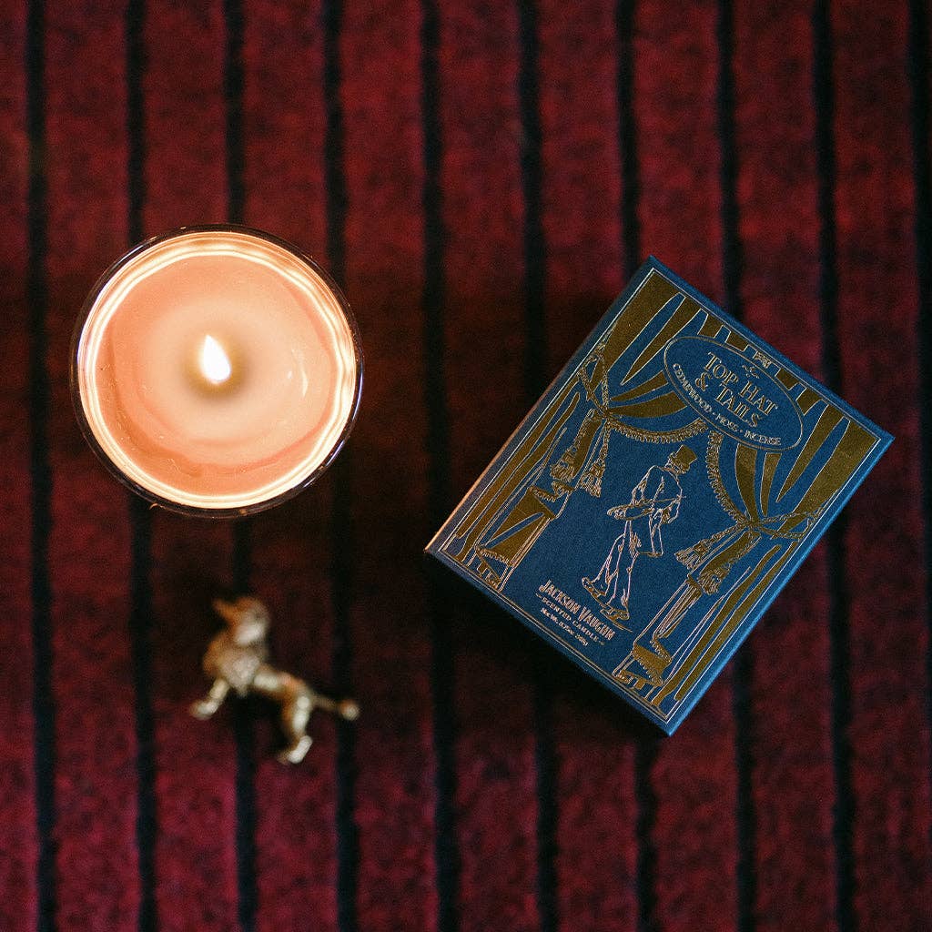 Candle and its packaging on a textured red surface
