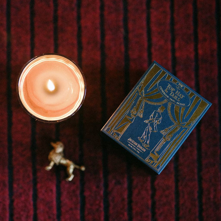 Candle and its packaging on a textured red surface
