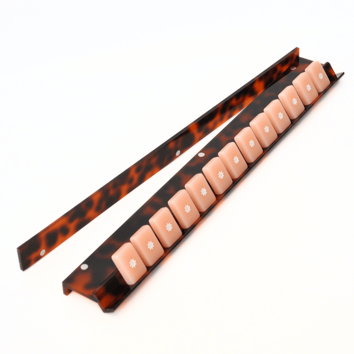 Set of mahjong tiles on a tortoiseshell rack with a white background
