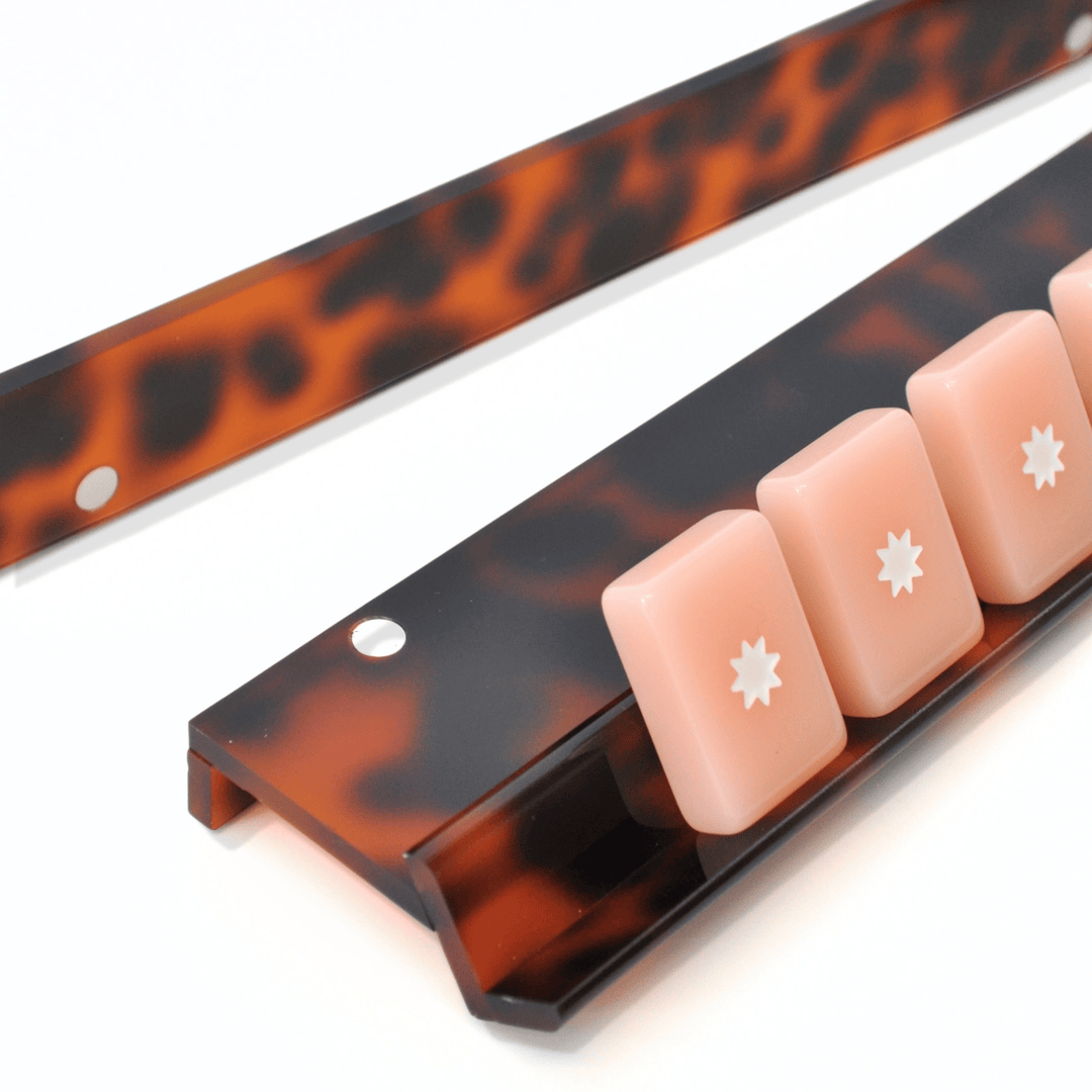 close-up of Tortoiseshell mahjong racks with pink mahjong tiles on a white background.