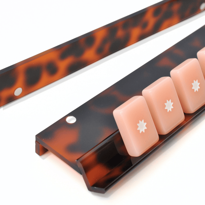 close-up of Tortoiseshell mahjong racks with pink mahjong tiles on a white background.